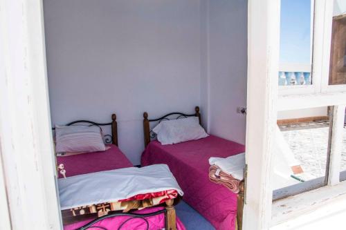 Duas camas num pequeno quarto com lençóis cor-de-rosa em Laverie du Soleil Surf House em Taghazout