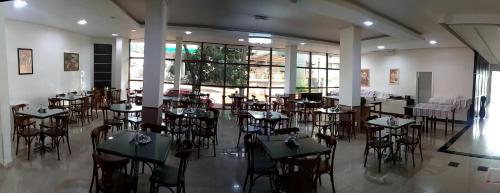 ein Restaurant mit Tischen und Stühlen in einem Zimmer mit Fenstern in der Unterkunft Hotel Maestro Villa Do Lago Toledo in Toledo