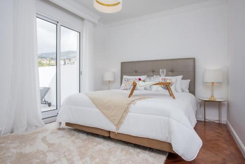 a white bedroom with a large bed and a window at Susy’s Garden in Funchal