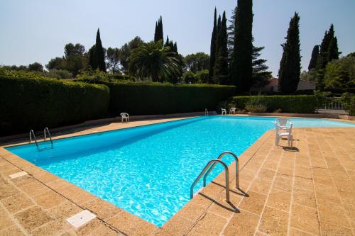 une piscine bleue avec 2 chaises et des arbres dans l'établissement Villa Ad Alta, à Cannes La Bocca