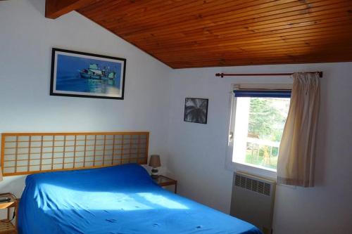sypialnia z niebieskim łóżkiem i oknem w obiekcie Chez Babeth w Tuluzie