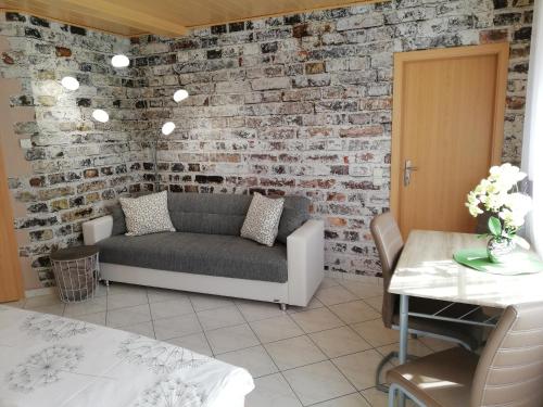 sala de estar con sofá y pared de ladrillo en Apartment Mona, en Wetzlar