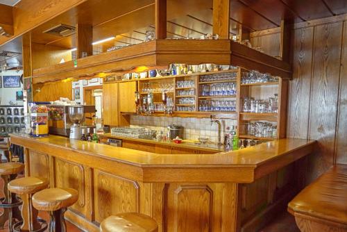 a bar in a restaurant with wooden walls and stools at Gasthof Podobnik in Bad Eisenkappel
