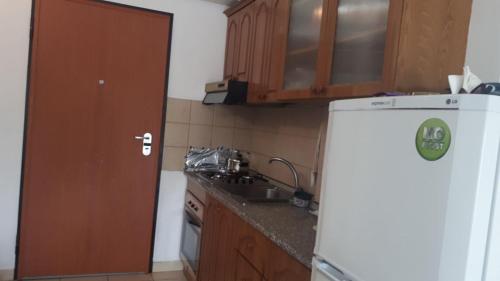 La cuisine est équipée d'un réfrigérateur blanc et de placards en bois. dans l'établissement Geni Apartment, à Durrës
