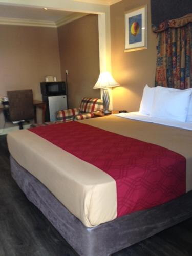 a hotel room with a large bed and a chair at Pacifica Motel in Long Beach