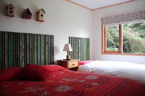 1 dormitorio con 2 camas y ventana en Cabañas Lomas del Lago, en Frutillar