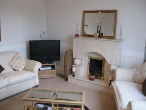 a living room with a fireplace and a tv at Kilkerran Guest House in Ayr