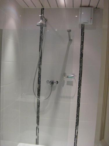a shower with a glass door with a shower head at Kilkerran Guest House in Ayr