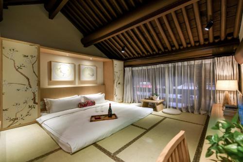 a bedroom with a large white bed and a window at Water Hotel, Pingyao in Pingyao