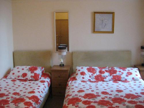 a bedroom with two beds with red and white sheets at Kilkerran Guest House in Ayr