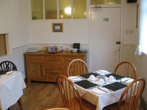 a dining room with a table and chairs and a kitchen at Kilkerran Guest House in Ayr