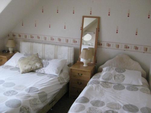 a bedroom with two twin beds and a mirror at Kilkerran Guest House in Ayr