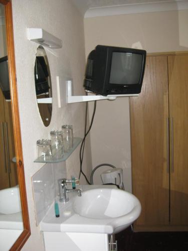 a bathroom with a sink and a tv on a wall at Kilkerran Guest House in Ayr