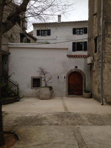 a large white building with a wooden door at cres art studio kuning apartment in Cres