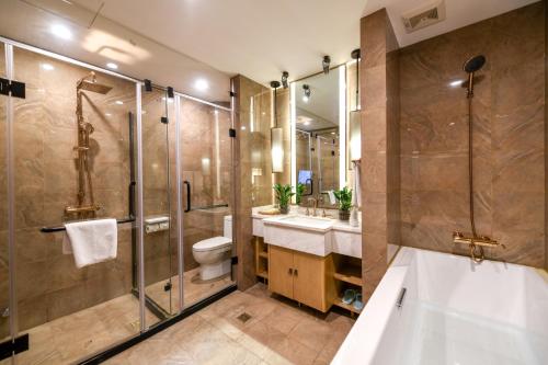 a bathroom with a tub and a toilet and a sink at Water Hotel, Pingyao in Pingyao