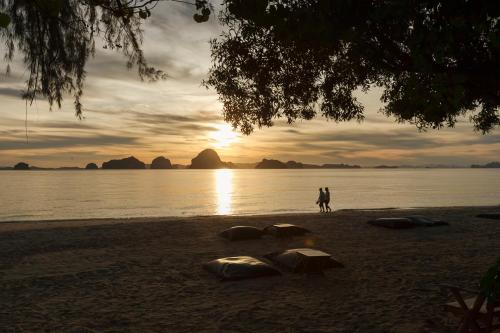 a person walking on a beach with rocks in the sand at The Tubkaak Krabi Boutique Resort in Tab Kaek Beach