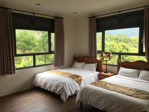 2 camas en una habitación con ventanas grandes en 闕麒景觀民宿Chill Villa B&B en Puli