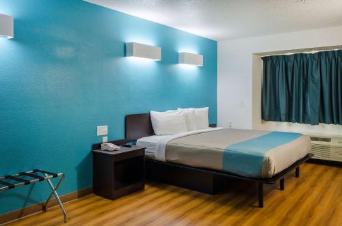 a room with a bed and a blue wall at Motel 6-Mobile, AL in Tillmans Corner