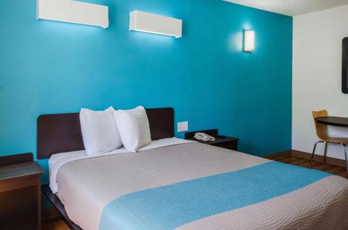 a bedroom with a bed with a blue wall at Motel 6-Mobile, AL in Tillmans Corner