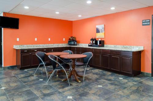 a kitchen with a table and chairs and orange walls at Motel 6-Mobile, AL in Tillmans Corner