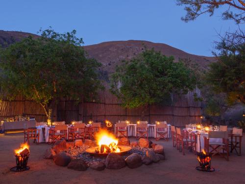 eine Gruppe von Tischen und Stühlen mit Kamin vor einer Feuerstelle in der Unterkunft Nkomazi Game Reserve by NEWMARK in Badplaas