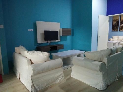 ein Wohnzimmer mit 2 Stühlen und einem TV in der Unterkunft Xenia Homestay in Kuching
