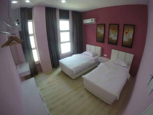 1 dormitorio con 2 camas y pared de color rosa en Xenia Homestay, en Kuching