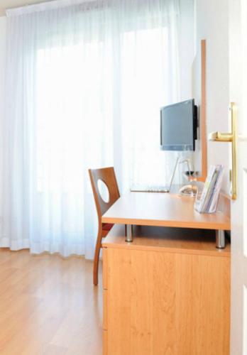 a desk with a computer and a chair in a room at Séjours & Affaires Lyon Park Lane in Lyon