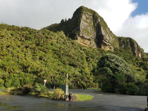 a mountain with a road in front of it at Punakaiki Rocks Hotel & Garden Bar in Punakaiki