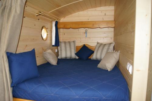 Bett in einer Hütte mit blauer Bettwäsche und Kissen in der Unterkunft Les Roulottes de Saint-Sulpice in Saint-Sulpice-en-Pareds