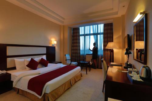 a hotel room with a bed and a desk and a window at Harmony Hotel in Addis Ababa