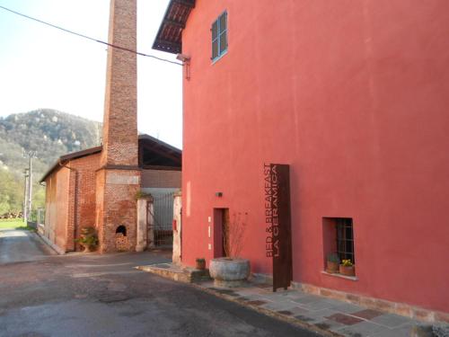 a red building with a tower on a street at B&B La Ceramica Moline in Vicoforte
