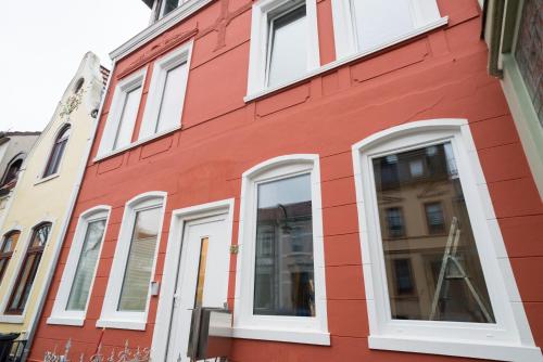 un edificio rojo con ventanas blancas en una calle en FeWo Engler Bremen Ritterhuder Straße, en Bremen