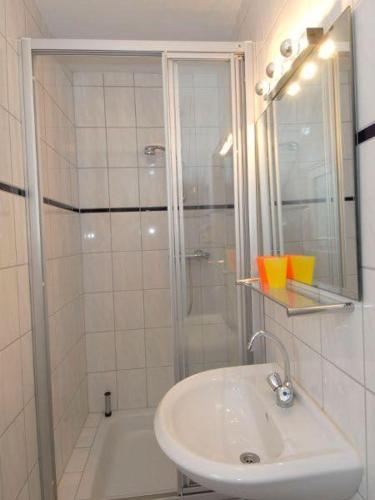 ein weißes Bad mit einer Dusche und einem Waschbecken in der Unterkunft Grenzhof, Elisabethwohnung in Westerland