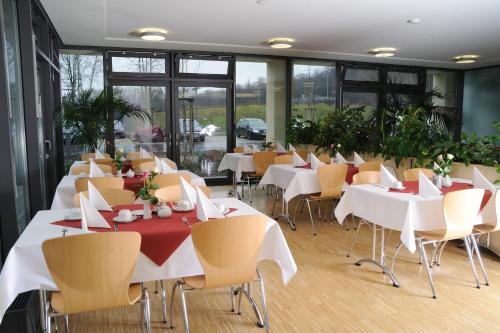 a restaurant with white tables and chairs and windows at Sporthotel Borussia Düsseldorf in Düsseldorf