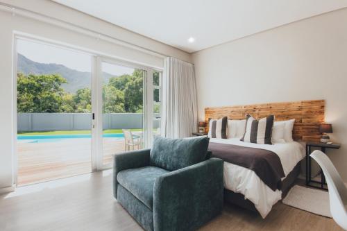 a bedroom with a bed and a chair and a pool at A Riverbed Guesthouse in Swellendam