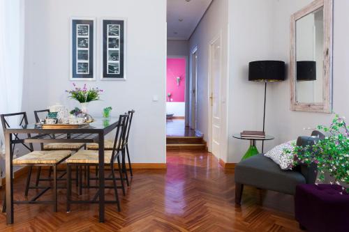 a dining room and living room with a table and chairs at Elegante piso junto al Museo del Prado in Madrid