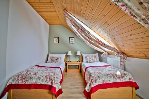 2 Betten in einem Zimmer mit Holzdecke in der Unterkunft Penzion Karlštejn in Karlštejn