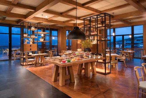 a dining room with tables and chairs and windows at Jinmao Pureal Mountain Liiang in Lijiang