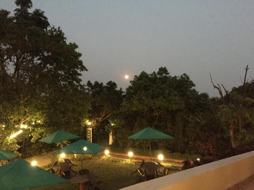 a group of tables with umbrellas at night at Honeywood Holiday Homes in Mahabaleshwar