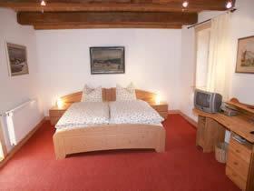 a bedroom with a large bed and a television at Pension Picco-Bello in Clausthal-Zellerfeld
