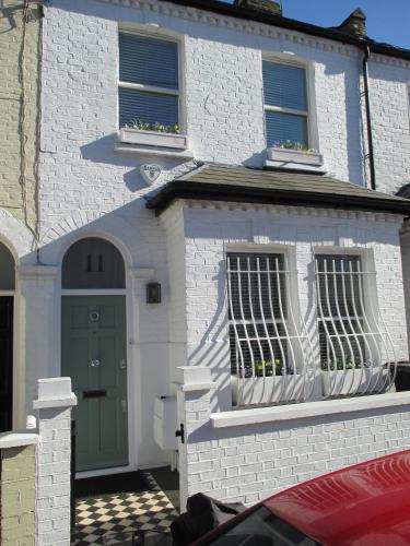 a white brick house with a green door and windows at Fulham B&B in London