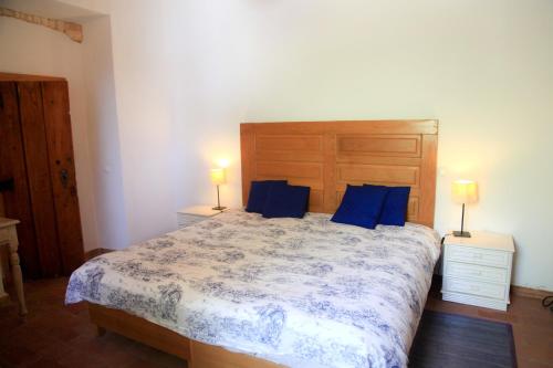 a bedroom with a large bed with blue pillows at Quinta Teresinha in Estômbar