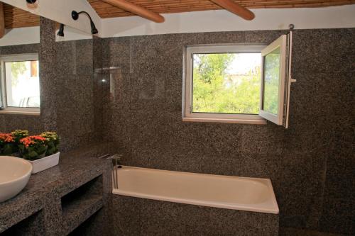 a bathroom with a tub and a sink and a window at Quinta Teresinha in Estômbar
