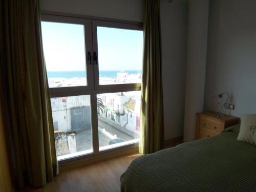 a bedroom with a large window with a view of the ocean at Apt. Alegria in Conil de la Frontera