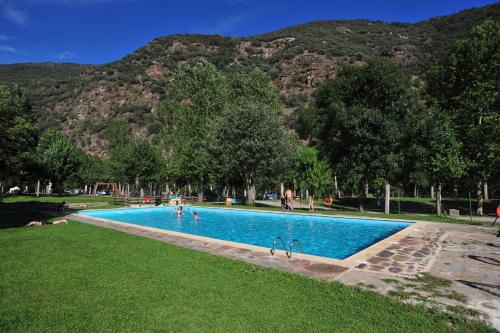 a swimming pool with people in it with mountains in the background at Camping Noguera Pallaresa in Sort