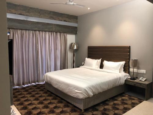 een slaapkamer met een groot wit bed en een raam bij Hotel Sharanam in Shegaon