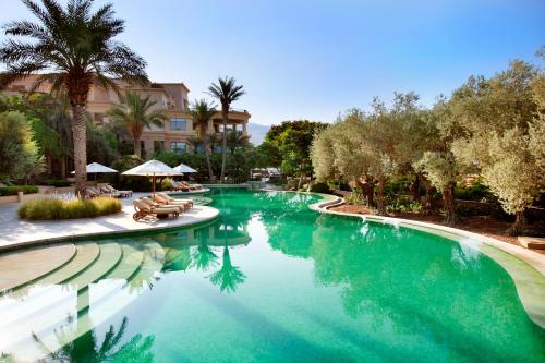 a swimming pool with chairs and trees in a resort at Kempinski Hotel Ishtar Dead Sea in Sowayma