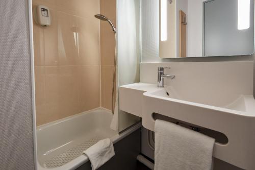 La salle de bains blanche est pourvue d'un lavabo et d'une douche. dans l'établissement B&B HOTEL Cherbourg, à Cherbourg en Cotentin