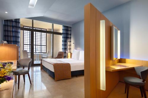 a hotel room with a bed and a table and chairs at Kempinski Hotel Ishtar Dead Sea in Sowayma